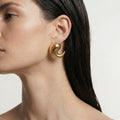 Single Courbe gold earring shown worn, showing its smooth curled comma form